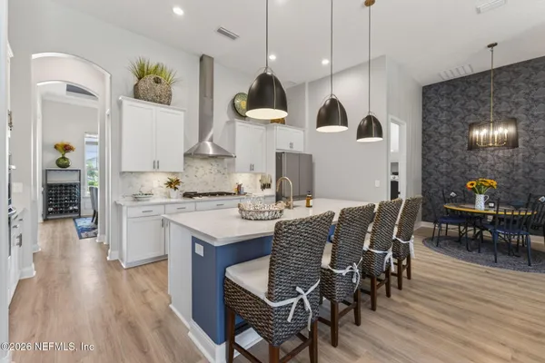 a large room with a chandelier fan and kitchen view