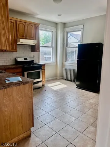 a kitchen with granite countertop a stove a sink a refrigerator and cabinets