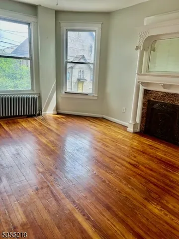 an empty room with wooden floor fireplace and windows