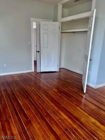 a view of an empty room with wooden floor and closet