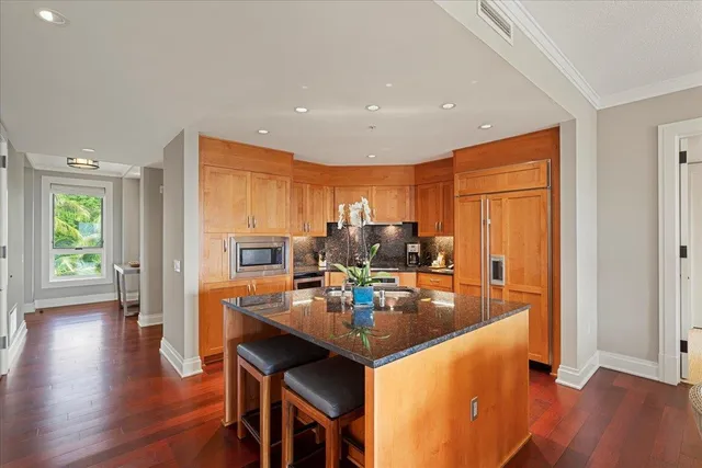 a dining hall with stainless steel appliances granite countertop a sink refrigerator and wooden floor