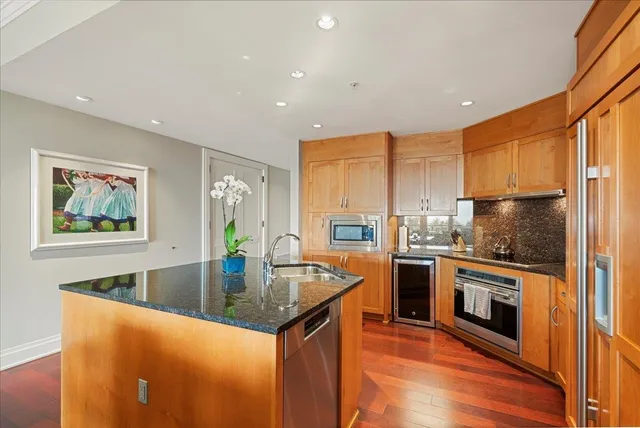 a kitchen with stainless steel appliances granite countertop a sink a stove and a refrigerator
