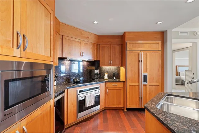 a kitchen with a sink wooden floor and stainless steel appliances