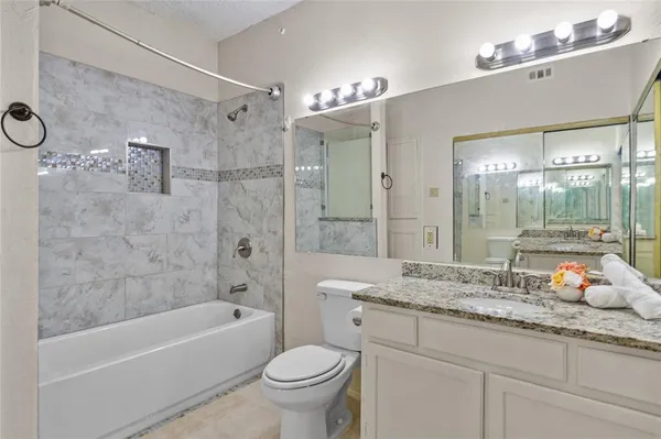 a bathroom with a granite countertop sink mirror toilet and bathtub