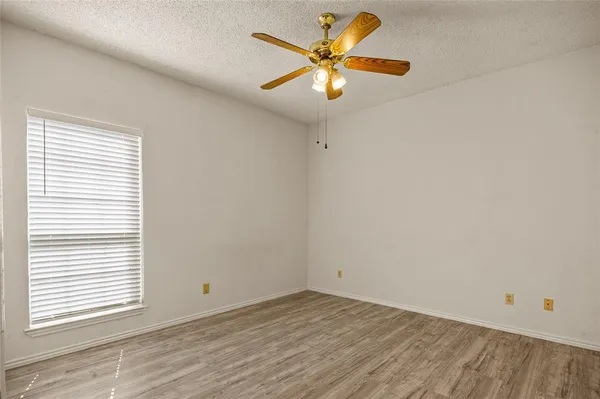 an empty room with a window and a fan