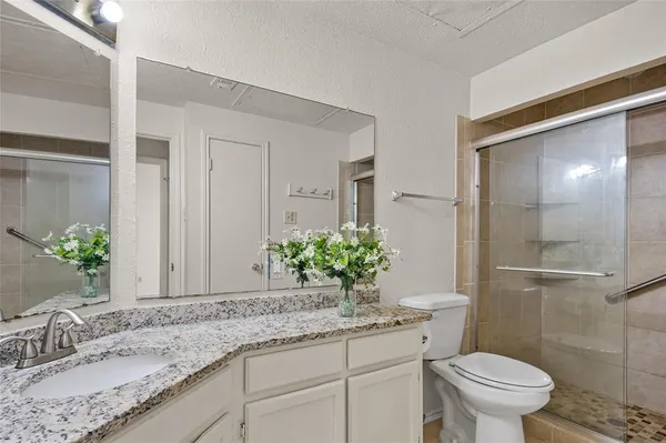 a bathroom with a granite countertop sink toilet and a mirror