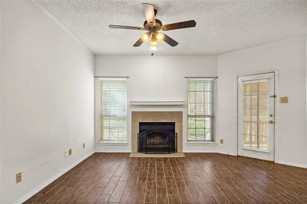 a view of an empty room with wooden floor fireplace and a window