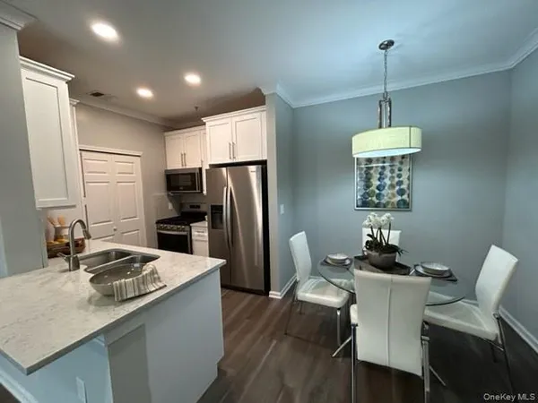 a kitchen with stainless steel appliances granite countertop a dining table chairs refrigerator and sink