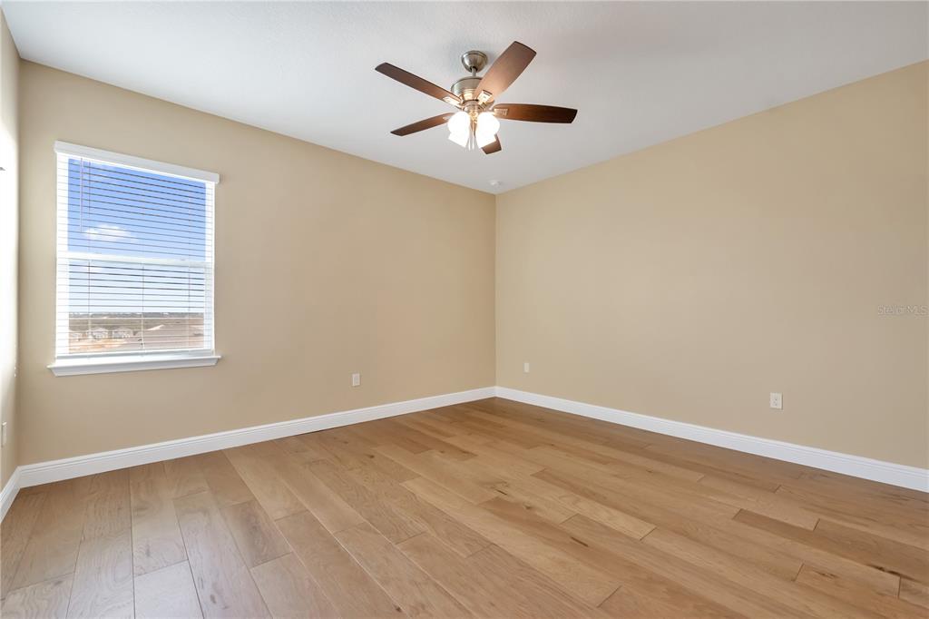 2132 Keystone Pass Boulevard Minneola, FL 34715 - Photo 16 of 52 a view of an empty room with wooden floor and a ceiling fan