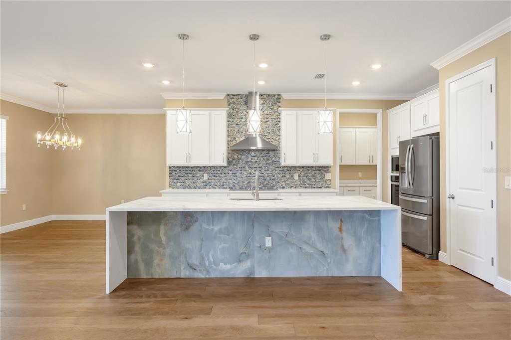 2132 Keystone Pass Boulevard Minneola, FL 34715 - Photo 9 of 52 a view of kitchen island wooden floor cabinets and stainless steel appliances