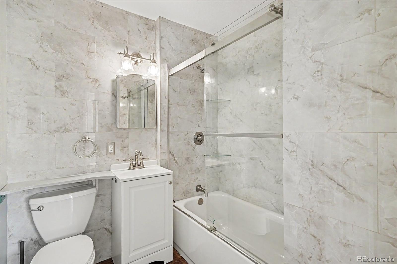 3217 South Stuart Street Denver, CO 80236 - Photo 22 of 29 a bathroom with a bathtub shower sink mirror and toilet