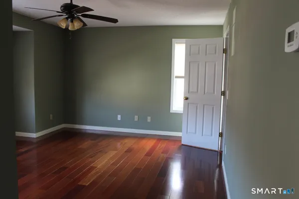 a view of an empty room with wooden floor and a window