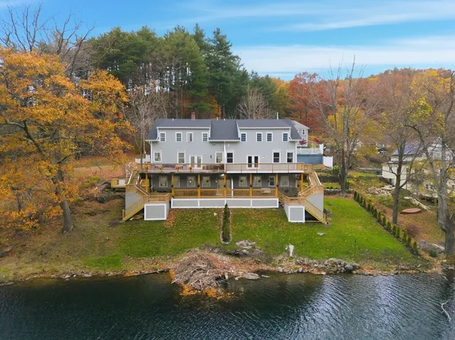 a kitchen with stainless steel appliances kitchen island granite countertop a dining table chairs and a refrigerator