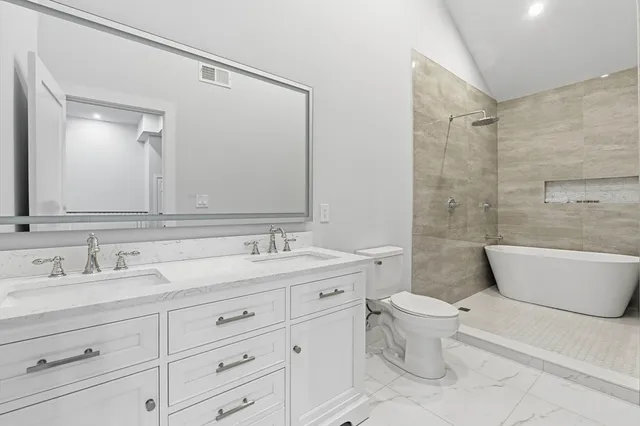 a bathroom with a toilet a sink a bathtub and a mirror