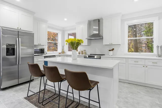 a kitchen with stainless steel appliances a dining table chairs refrigerator and sink