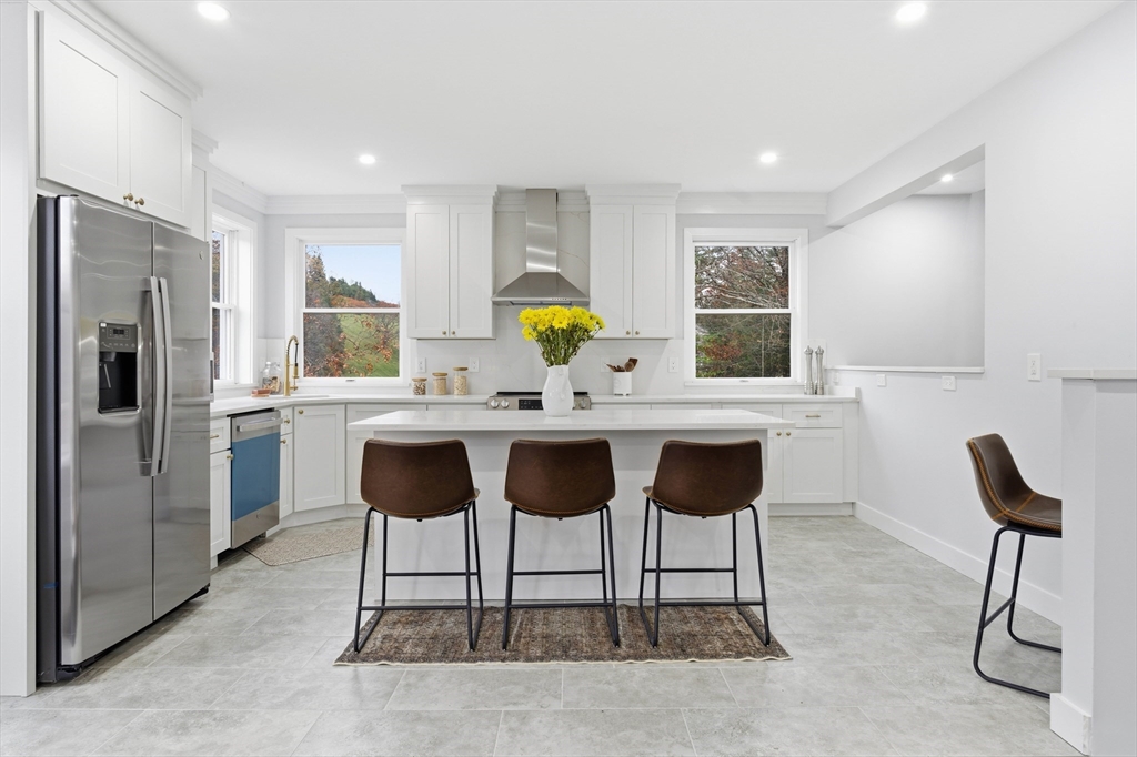 288 Grove Street, Unit 288 Clinton, MA 01510 - Photo 8 of 37 a kitchen with stainless steel appliances kitchen island granite counter tops chairs and a refrigerator