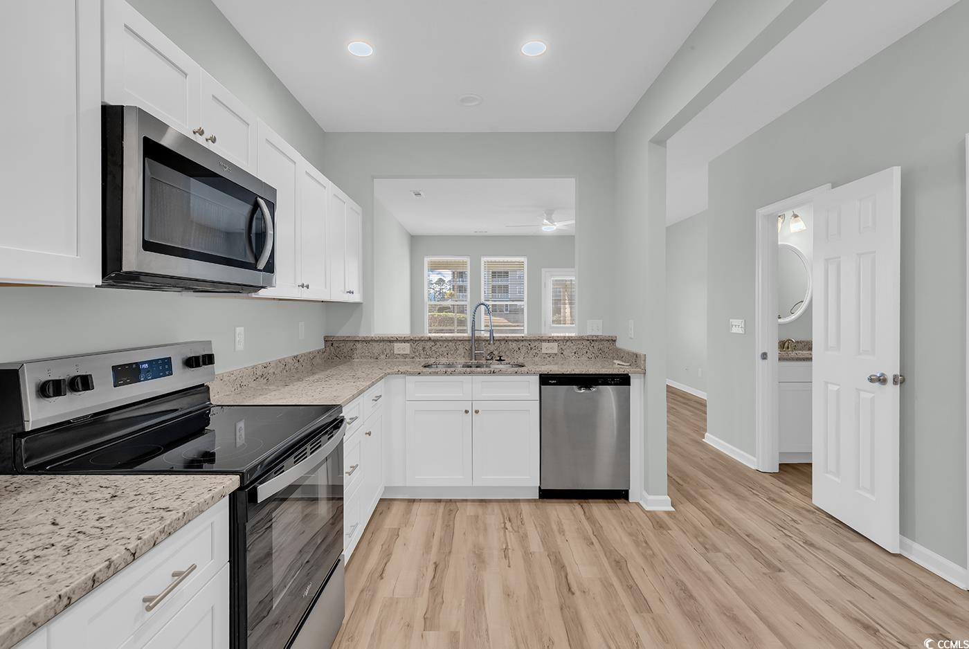 308 Kiskadee Loop, Unit E Conway, SC 29526 - Photo 8 of 36 Kitchen featuring stainless steel appliances, white cabinets, light stone countertops, light wood-type flooring, and a peninsula