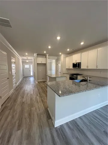 a large kitchen with stainless steel appliances granite countertop a large counter top and a stove with wooden floors