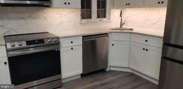 a kitchen with granite countertop white cabinets appliances and a sink