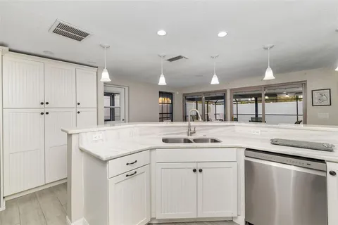 a kitchen with stainless steel appliances a refrigerator a stove a sink dishwasher with wooden cabinets and chair