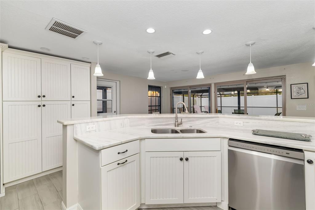 410 Pameto Road Nokomis, FL 34275 - Photo 14 of 40 a kitchen with a sink dishwasher and white cabinets with wooden floor