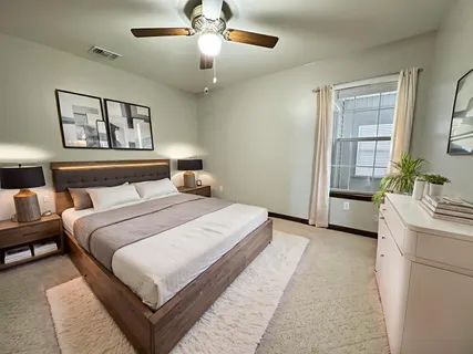 an empty room with a chandelier fan and windows