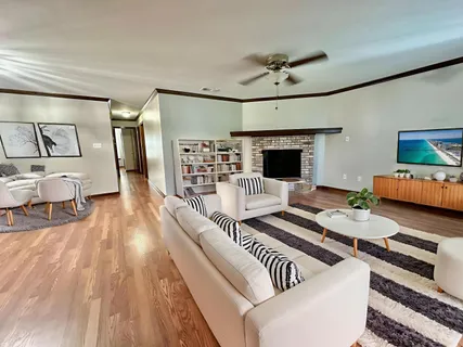 a view of an empty room with wooden floor fireplace and a window