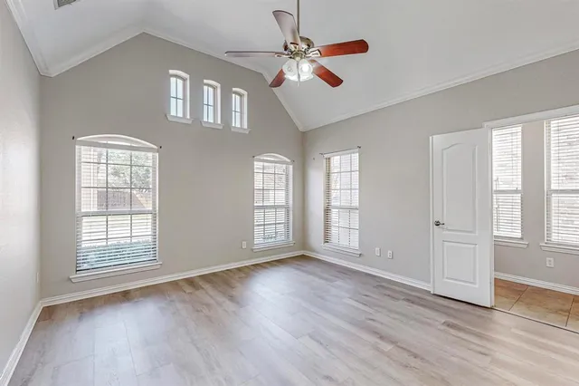 an empty room with wooden floor chandelier fan and windows