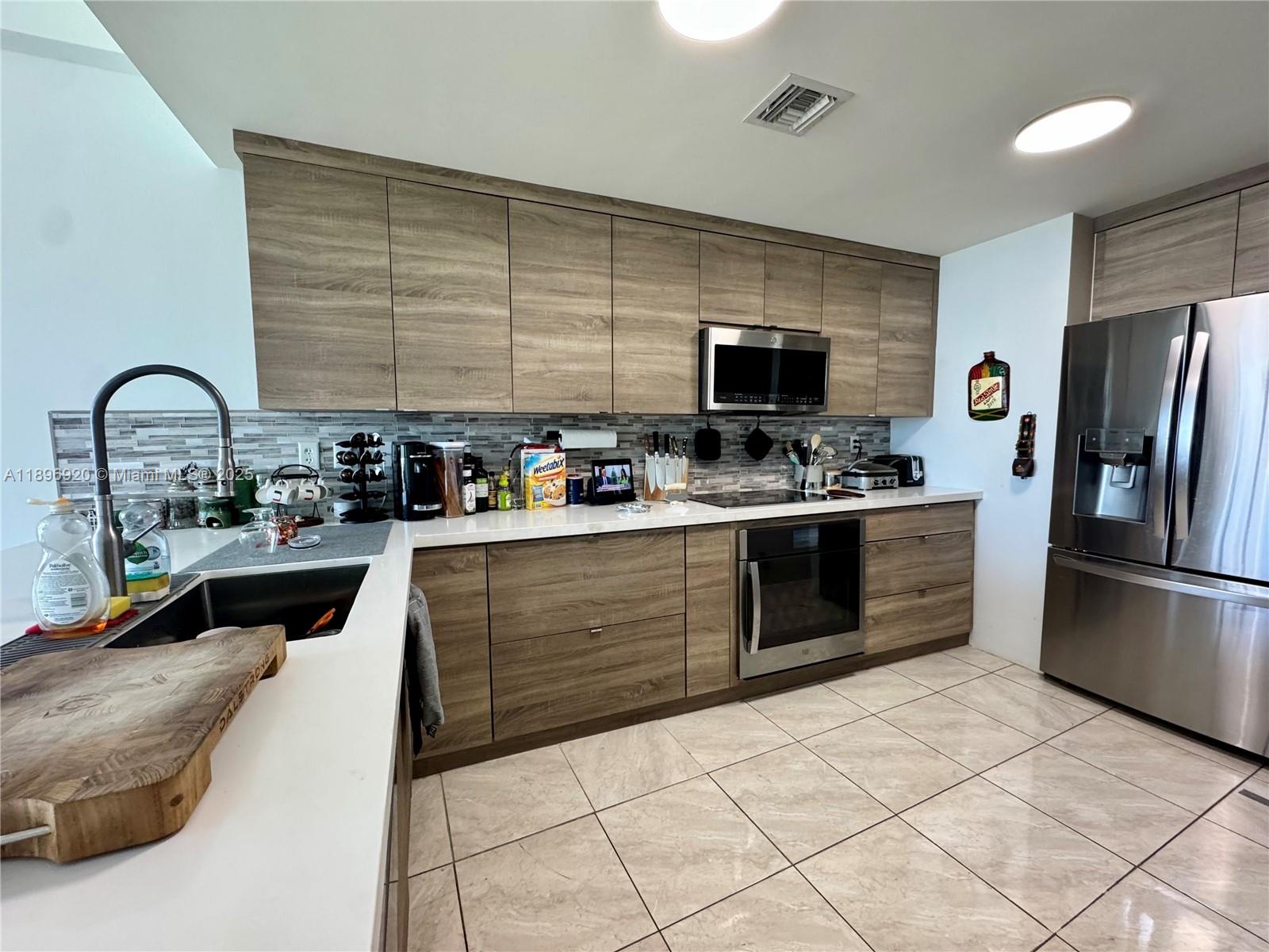 6580 Indian Creek Drive, Unit 404 Miami Beach, FL 33141 - Photo 13 of 19 a kitchen with stainless steel appliances kitchen island granite countertop a refrigerator and a stove top oven