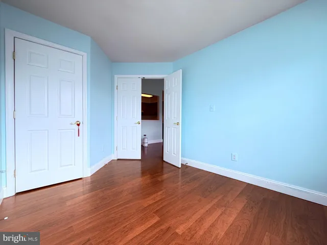 a view of an empty room with wooden floor and closet