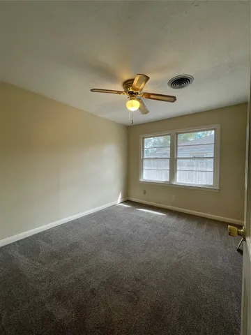 an empty room with a window and a ceiling fan