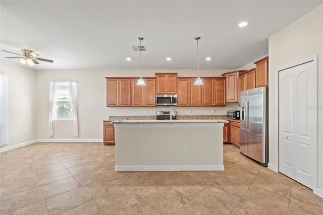 a view of kitchen with stainless steel appliances granite countertop a stove top oven a refrigerator a sink and a window