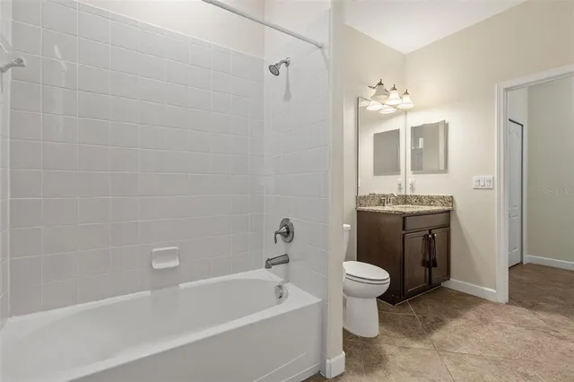 a bathroom with a granite countertop sink a toilet and a mirror