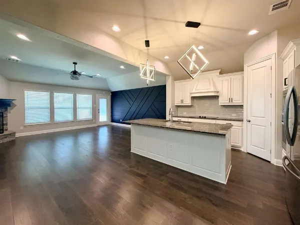 a kitchen with stainless steel appliances granite countertop a stove a refrigerator a sink dishwasher and a oven with wooden floor
