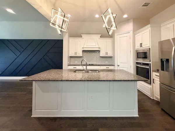 a kitchen with stainless steel appliances granite countertop a sink a microwave oven and a refrigerator with wooden floor