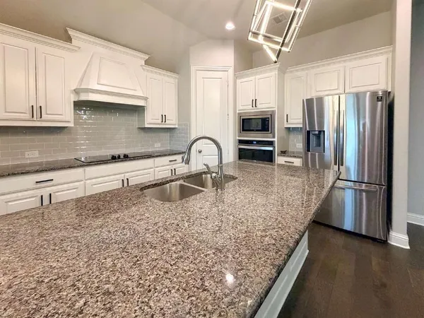 a kitchen with stainless steel appliances granite countertop a sink a stove and refrigerator