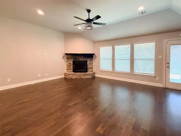 an empty room with wooden floor fan and windows
