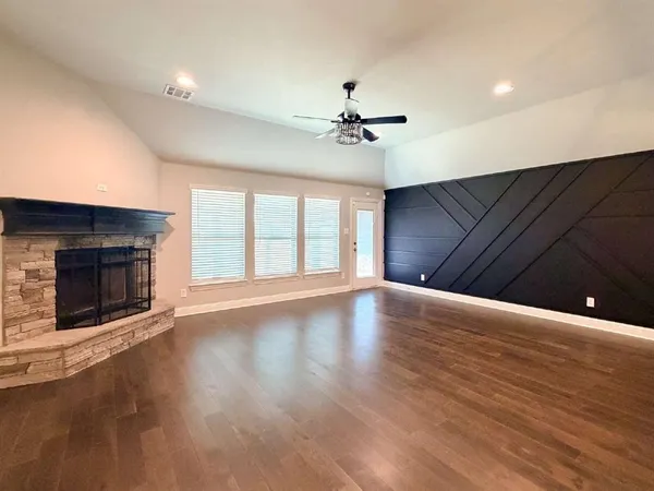 a view of an empty room with wooden floor fireplace and a window