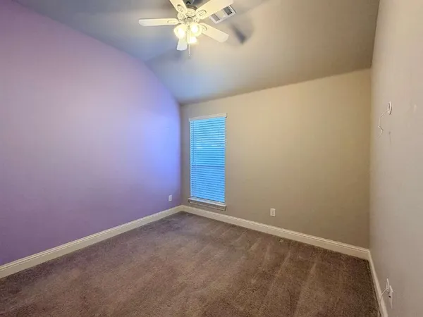 an empty room with a chandelier fan and closet