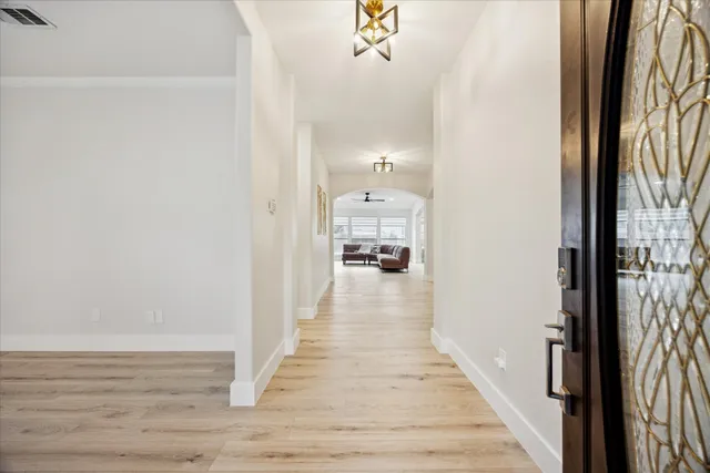 a view of a hallway with wooden floor and a chandelier