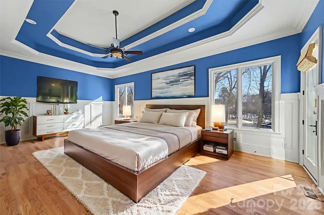 a spacious bedroom with a large bed a flat screen tv and a chandelier