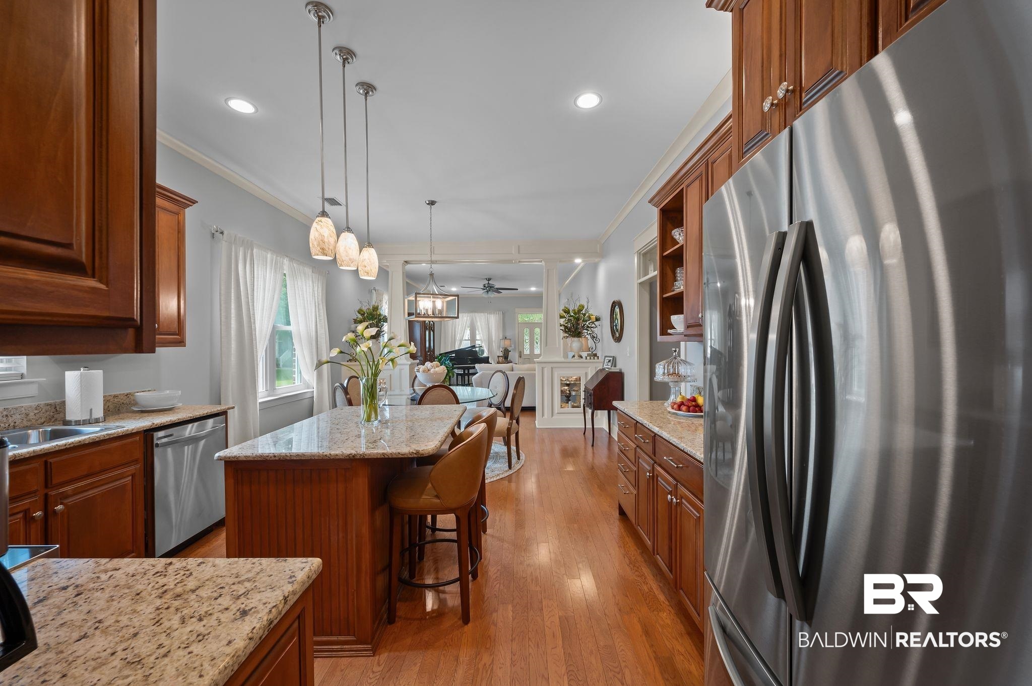 905 Buttercup Lane Foley, AL 36535 - Photo 25 of 47 Kitchen featuring appliances with stainless steel finishes, brown cabinetry, crown molding, a kitchen bar, and light wood finished floors