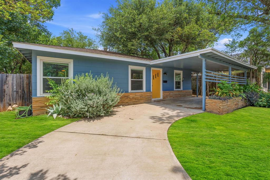 900 Stark Street Austin, TX 78756 - Photo 22 of 25 A charming blue home with a yellow door, featuring a carport and mature landscaping.