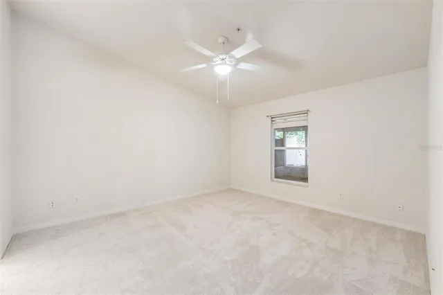 an empty room with a chandelier fan and windows