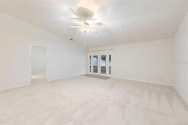 a view of an empty room with a chandelier fan