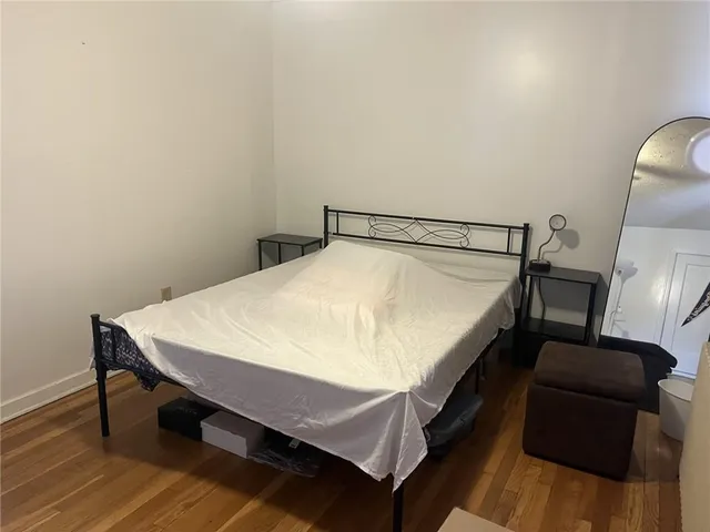 a bed sitting in a bedroom and wooden floor