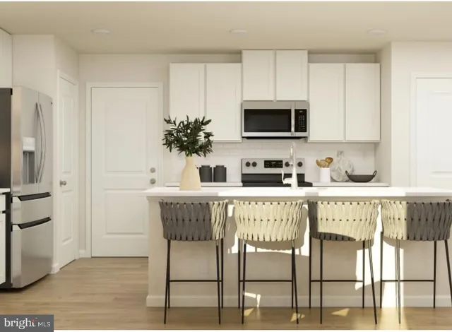 a kitchen with stainless steel appliances granite countertop a table chairs in it and white cabinets