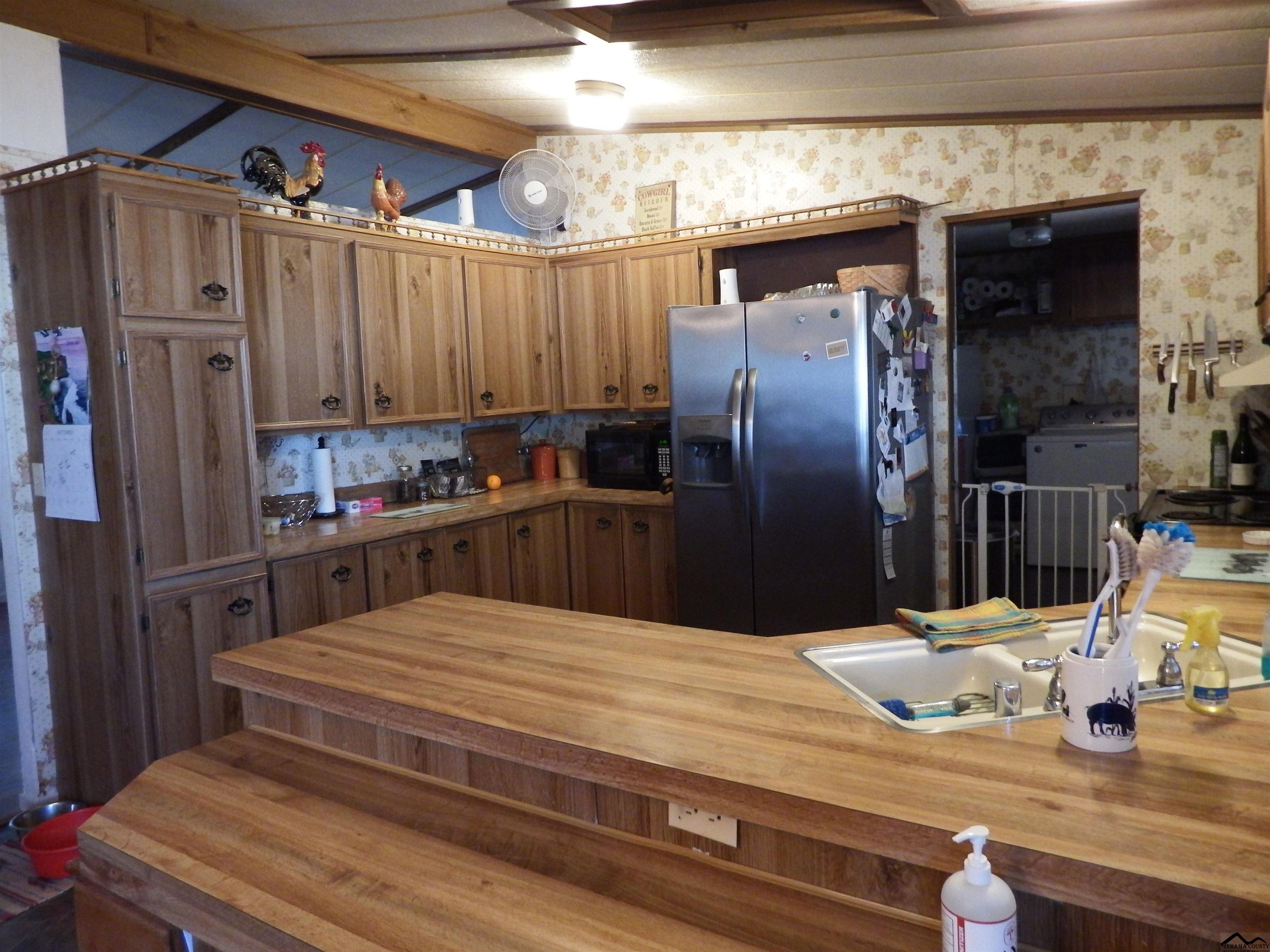 12535 Wilder Road Red Bluff, CA 96080 - Photo 16 of 30 a kitchen with kitchen island a counter top space a refrigerator and cabinets