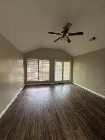 a view of empty room with wooden floor and fan