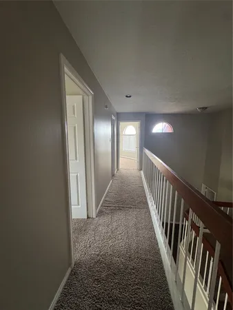a view of a hallway with wooden floor and stairs